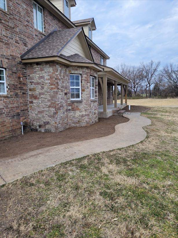 Clean, cleared yard alongside a stone home after tree work was finished